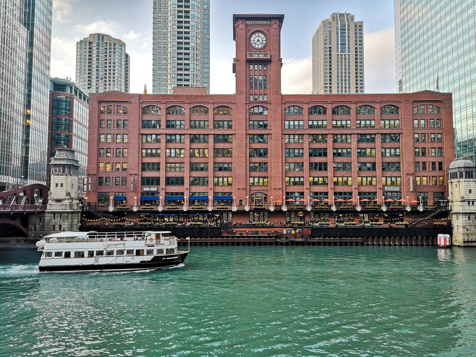 a boat traveling down a river past a tall building